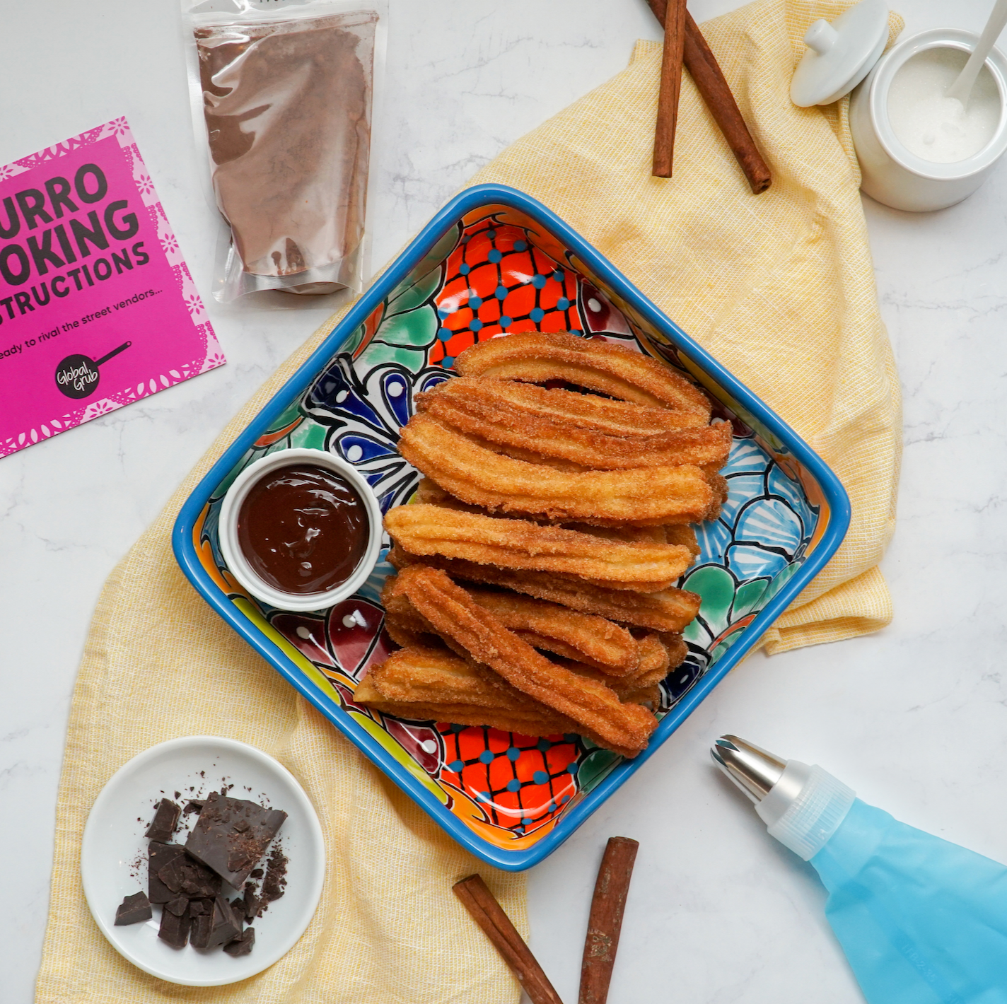 Churro with dipping chocolate and other ingredients and tools for this homemade treat